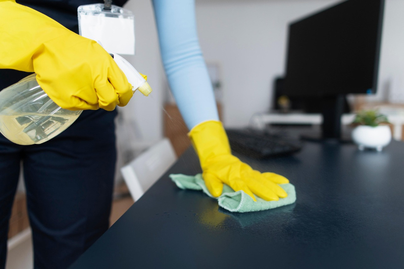 Unterhaltsreiniger säubert einen Bürotisch